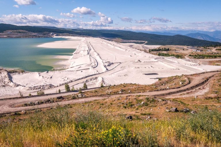 Barragem de rejeitos com lago à esquerda e montanhas ao fundo