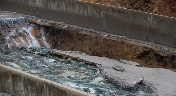 Vista localizada de um sistema extravasor de barragem de concreto com danos causados por erosão advinda de um processo de cavitação