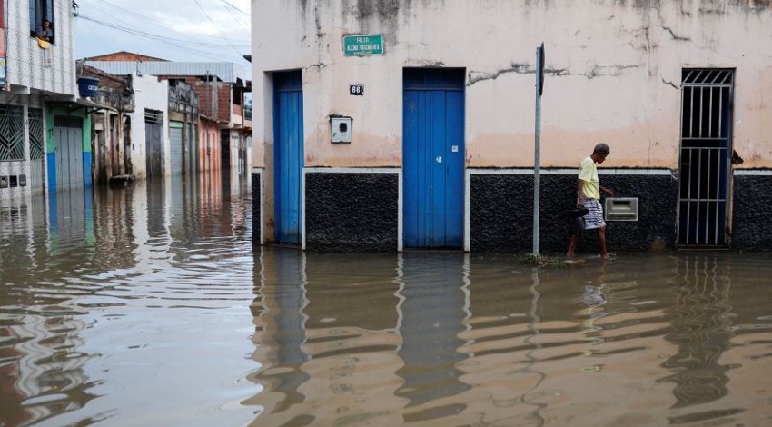 Fotografia do Jornal CNN. Mostra um homem caminhando em uma rua alagada, no estado da Bahia. 
Imagem utilizada para exemplificar os efeitos de eventos hidrológicos extremos.
